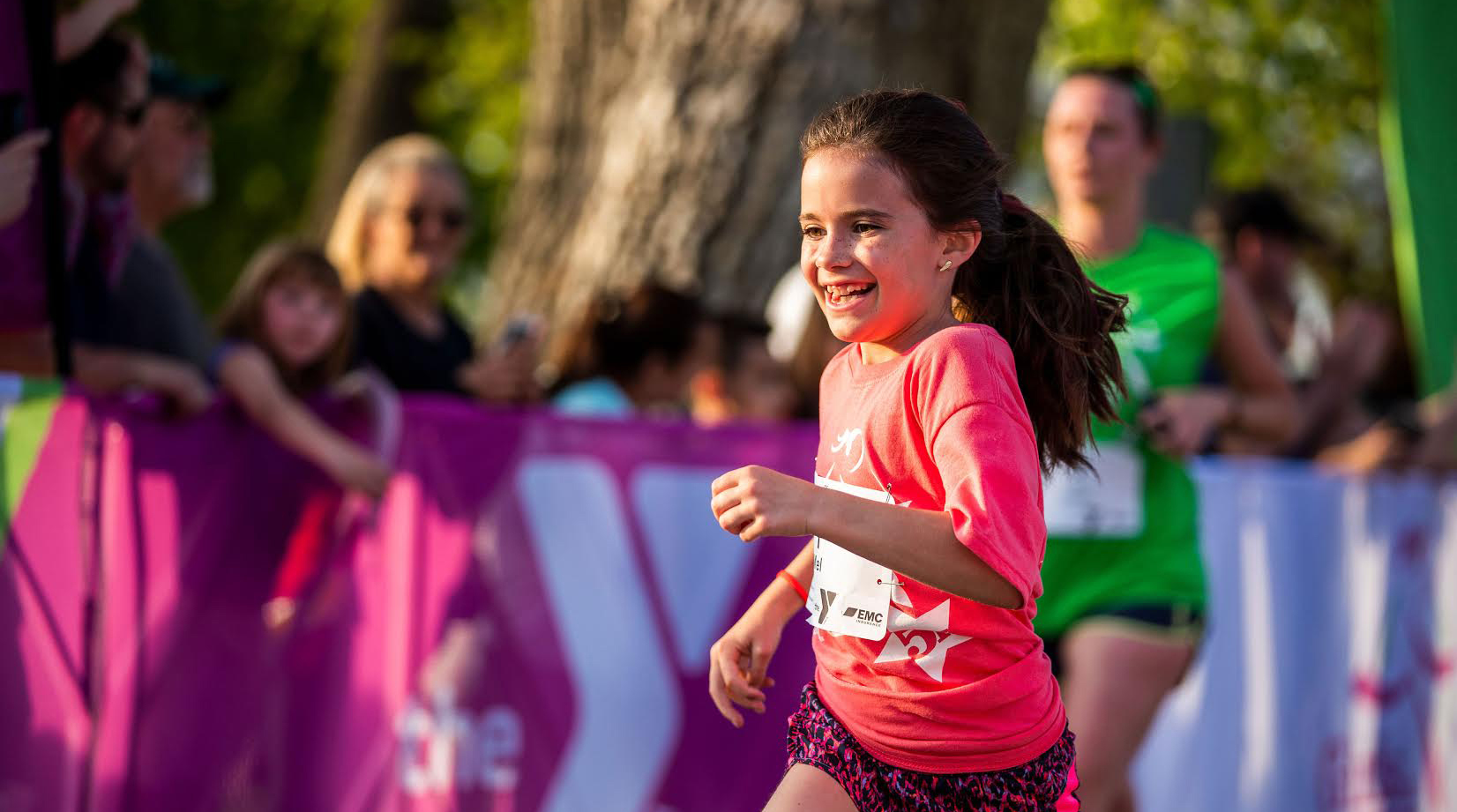 girl in pink shirt and shorts running while smiling